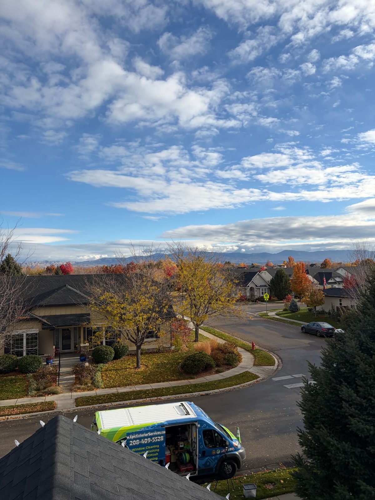 View from a lit roofline of fall trees, the Boise foothills and the Epic Exterior Services van