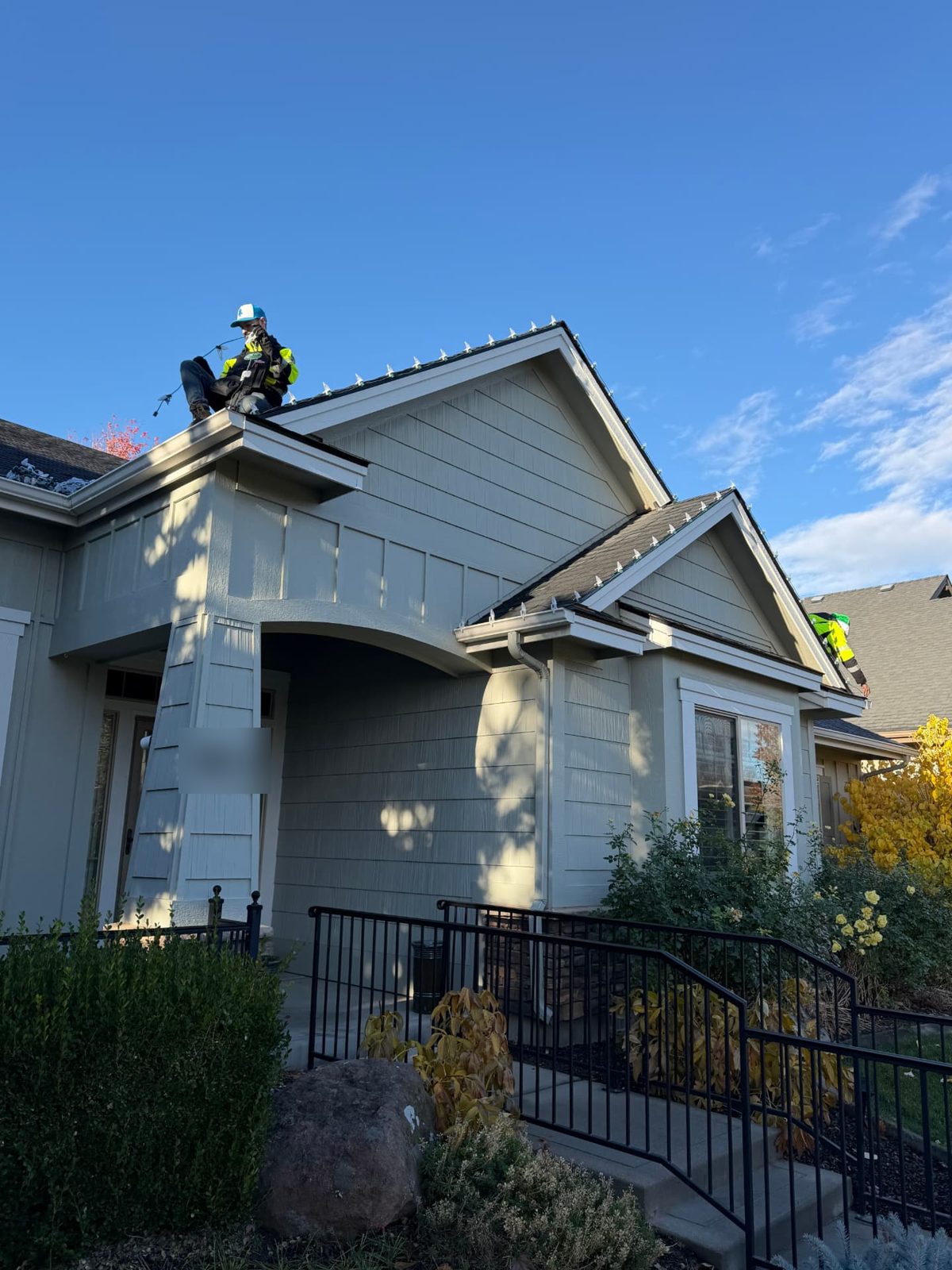 Two installers hanging warm white C9 lights along the peaks of a Boise-area home