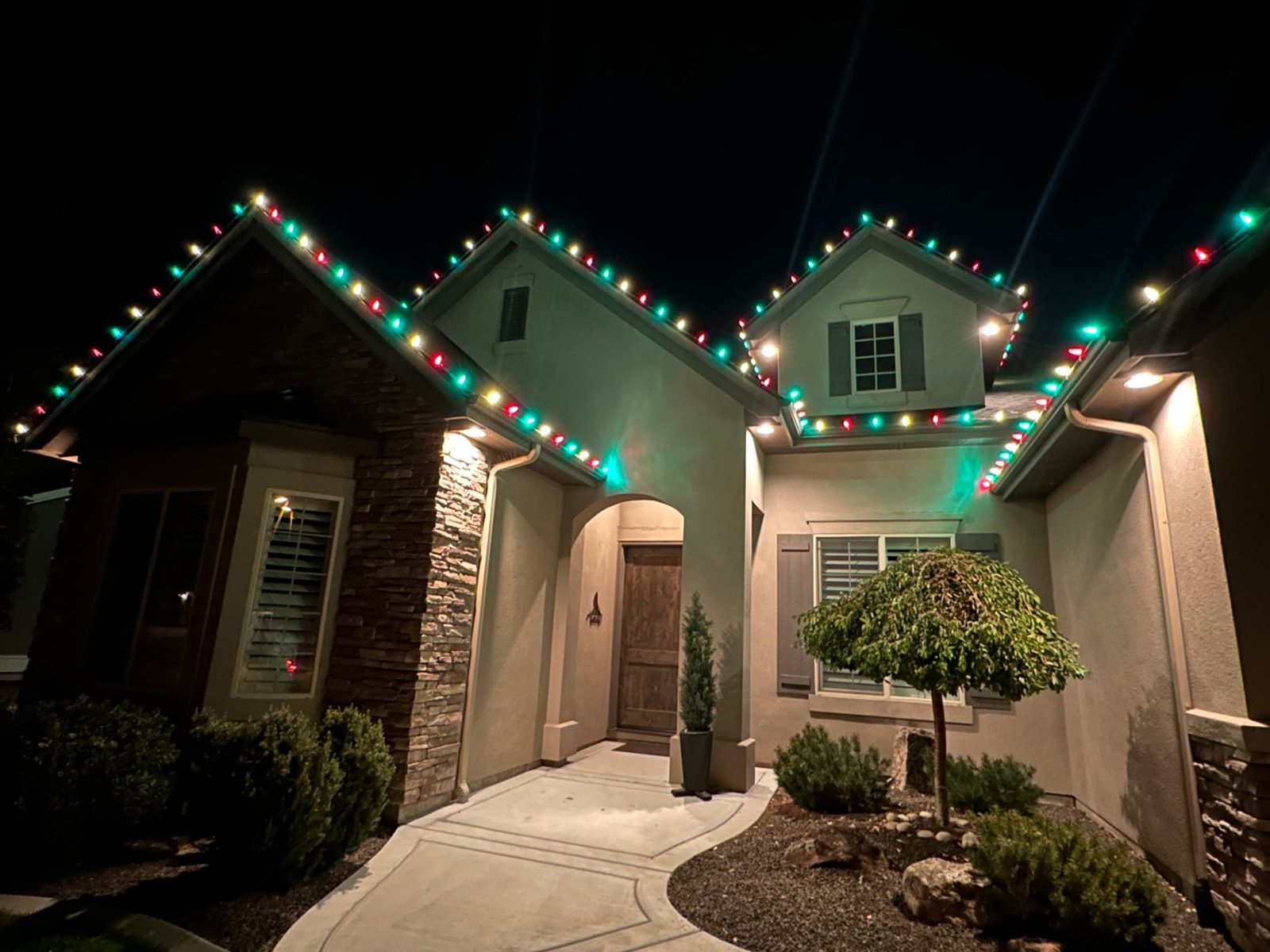Red, green and white C9 Christmas lights on a stucco home's peaks