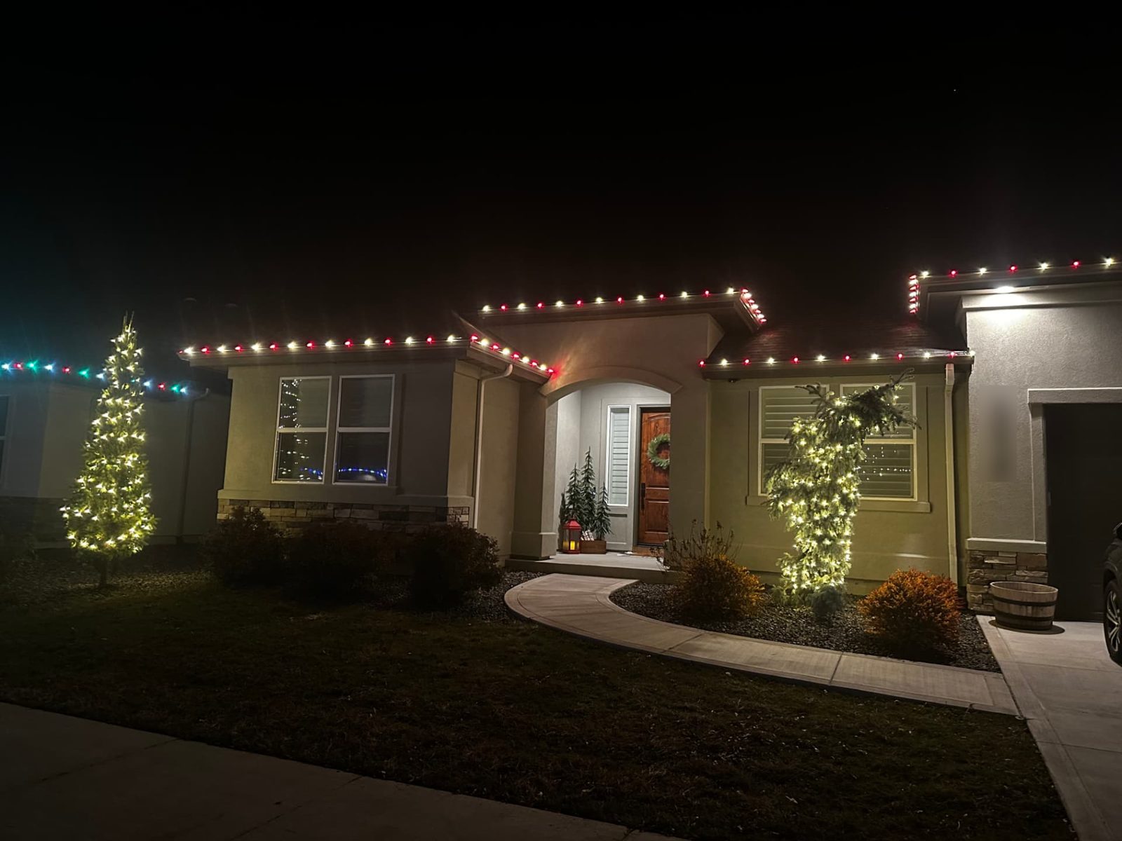 Red and white roofline lights with wrapped evergreen trees