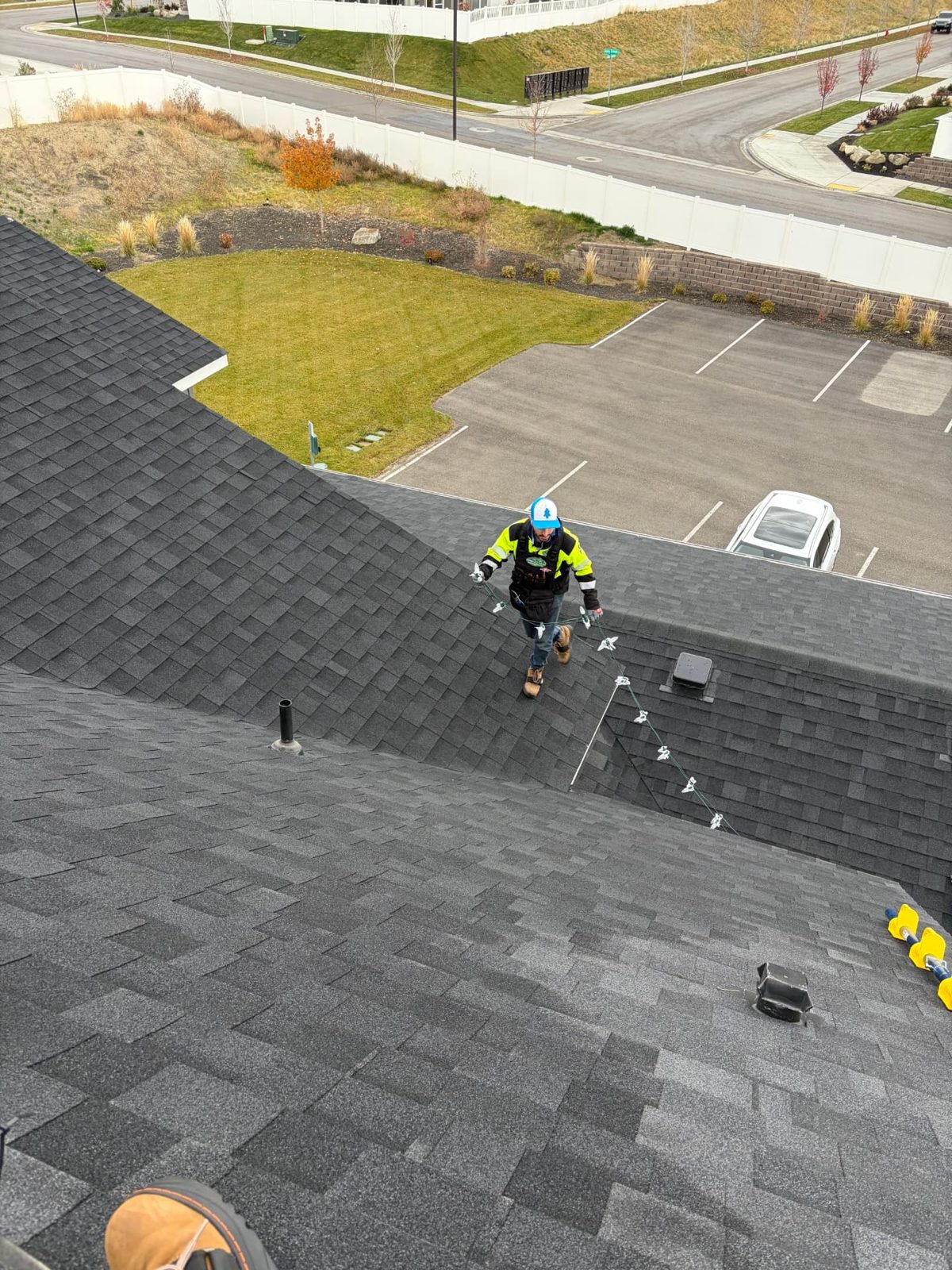 Crew member in hi-vis gear carrying a strand of light clips across a roof