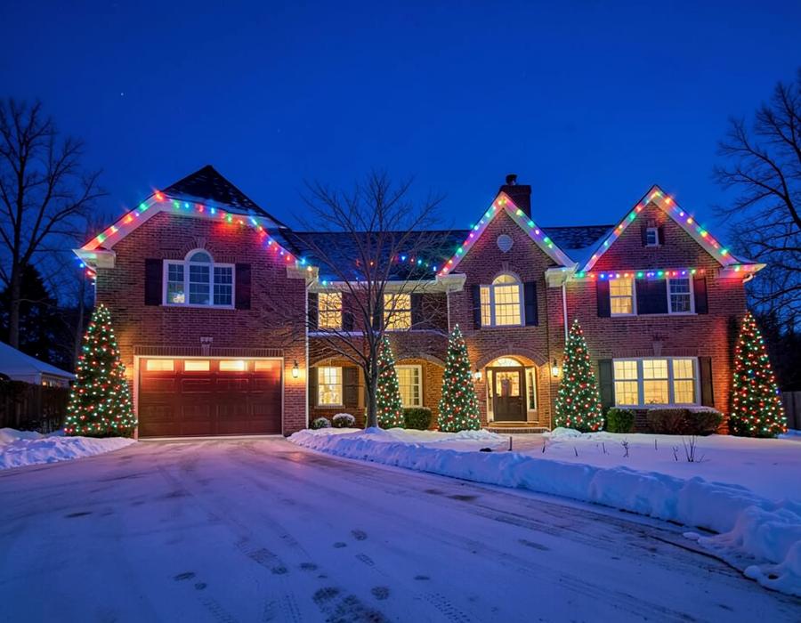 Brick home with multicolor Christmas lights and lit trees